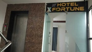 Entrada de un hotel con un cartel que dice "HOTEL FORTUNE" y una puerta de cristal.