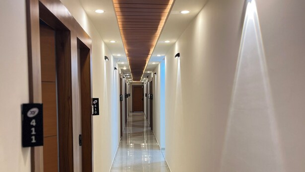Un pasillo largo y bien iluminado con suelo pulido, puertas de madera e iluminación empotrada en el techo.