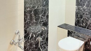 Un baño con ducha, inodoro y secamanos.