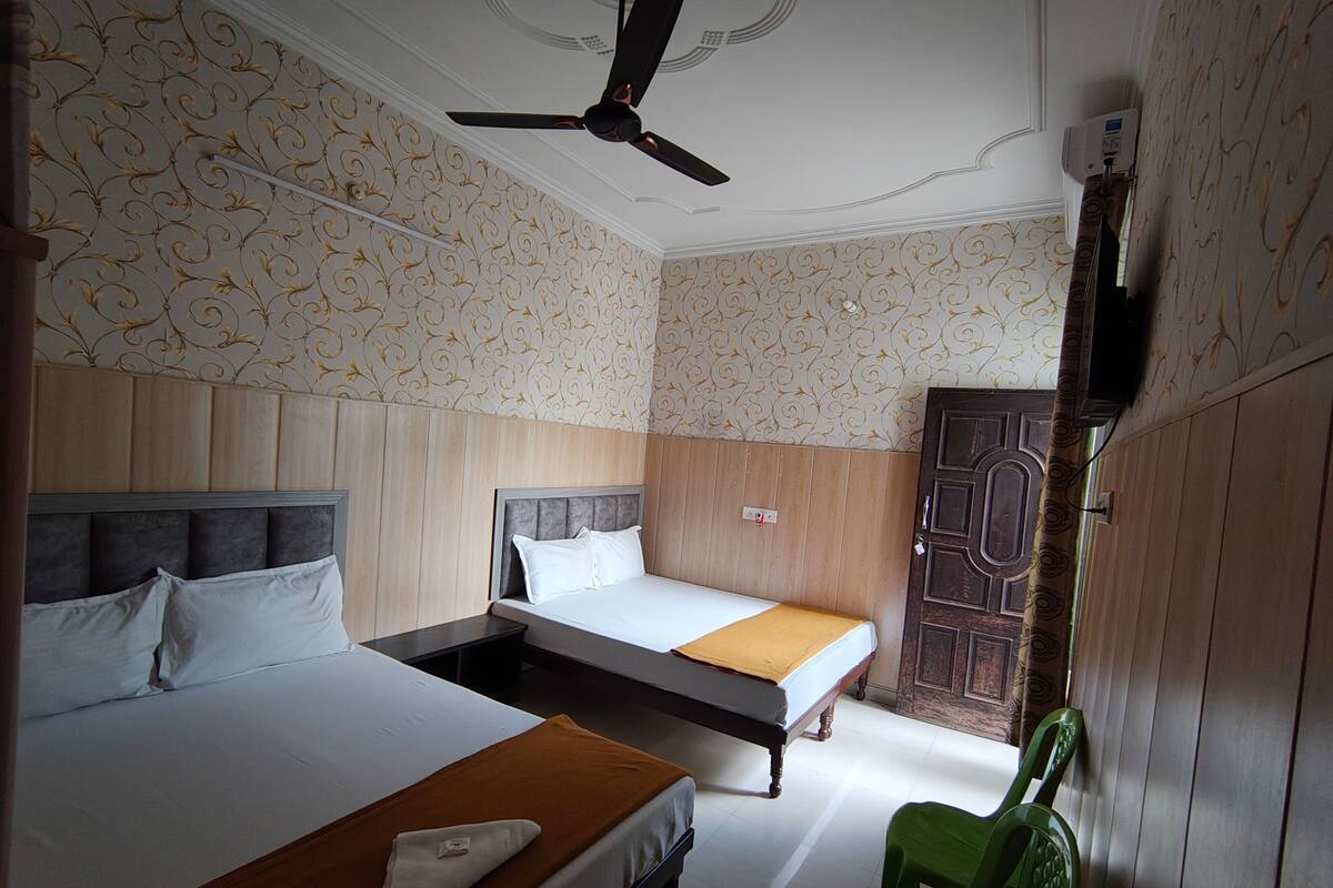 A hotel room with two beds, a ceiling fan, and patterned wallpaper.