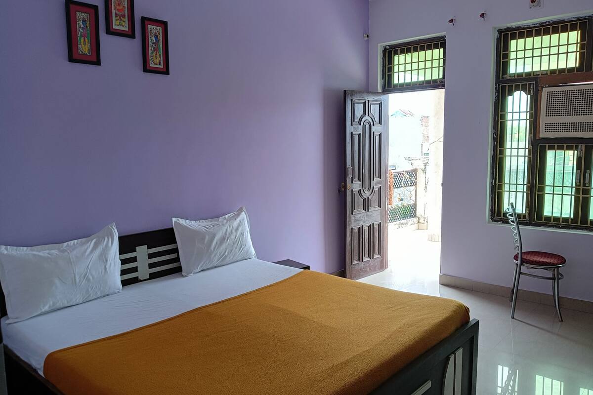 A bedroom with a bed, a window with bars, and a door leading outside.