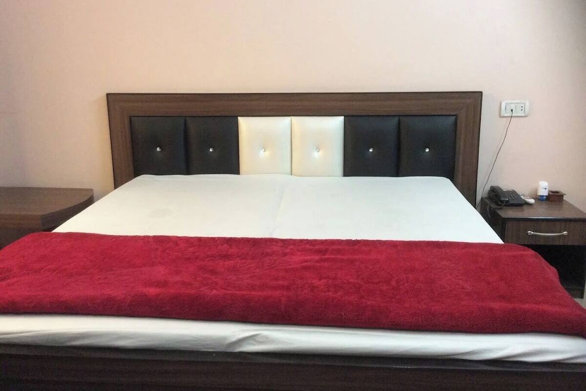 Een hotelkamer met een groot bed, een houten hoofdeinde, een nachtkastje en een bijzettafeltje.