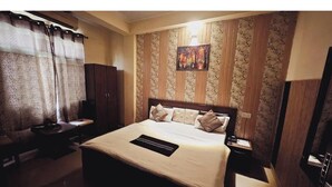 A hotel room with a bed, a desk, a chair, a nightstand, and a TV. - Hotel Golden Village Sidcul Haridwar (Haridwar)