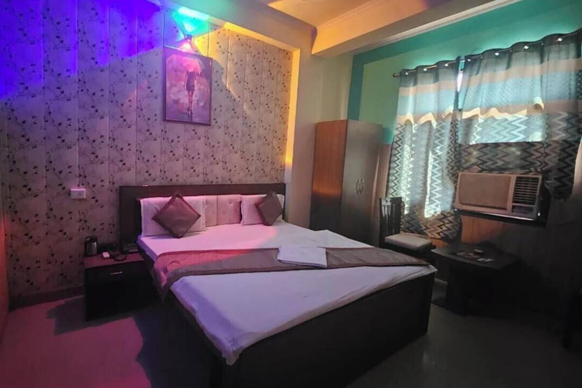 Een hotelkamer met een bed, nachtkastje en een raam met gordijnen.