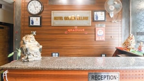 A reception desk with a clock, a sign for Hotel Golden Village, and a statue. - Hotel Golden Village Sidcul Haridwar (Haridwar)