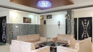 A modern living room with beige sofas, a glass coffee table, and a decorative ceiling light. - Hotel Golden Village Sidcul Haridwar (Haridwar)