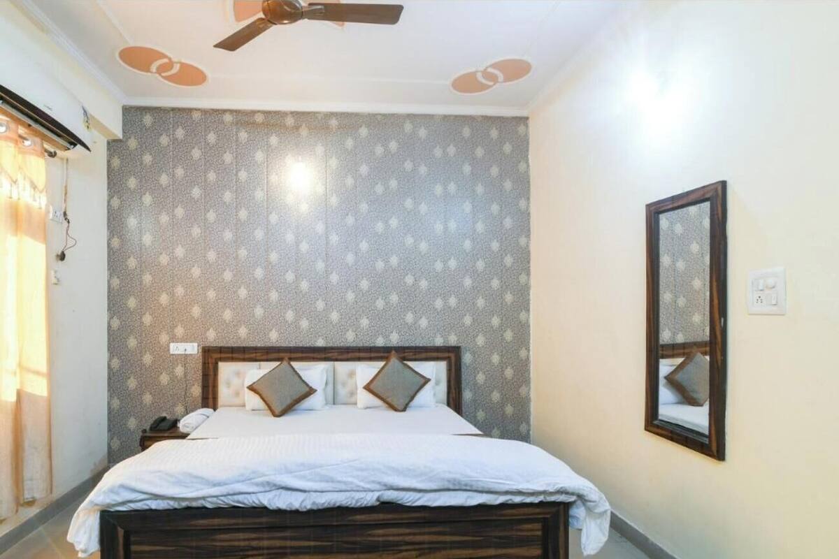 Een slaapkamer met een bed, een plafondventilator, een spiegel aan de muur en behang met een patroon.