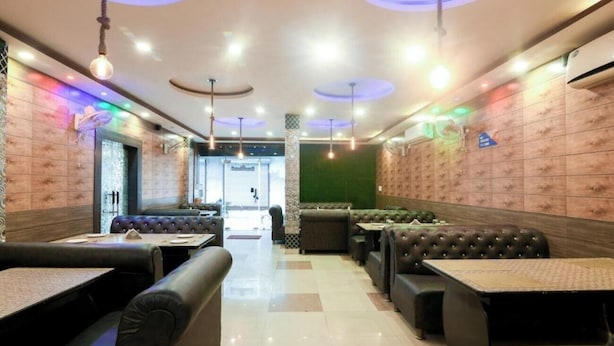 A restaurant interior with booths and tables, a tiled floor, and a green accent wall. - Hotel Golden Village Sidcul Haridwar (Haridwar)