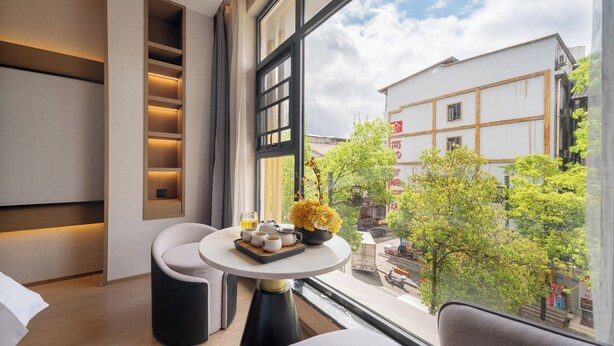 Una habitación moderna con un ventanal grande, una mesa redonda con un jarrón de flores y un sofá.