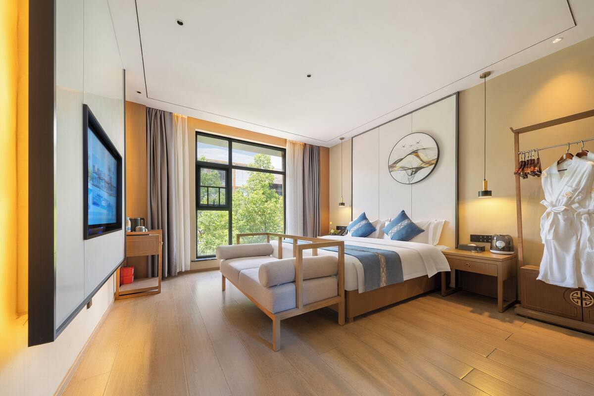 Habitación de hotel moderna con cama, mesita de noche y televisor.