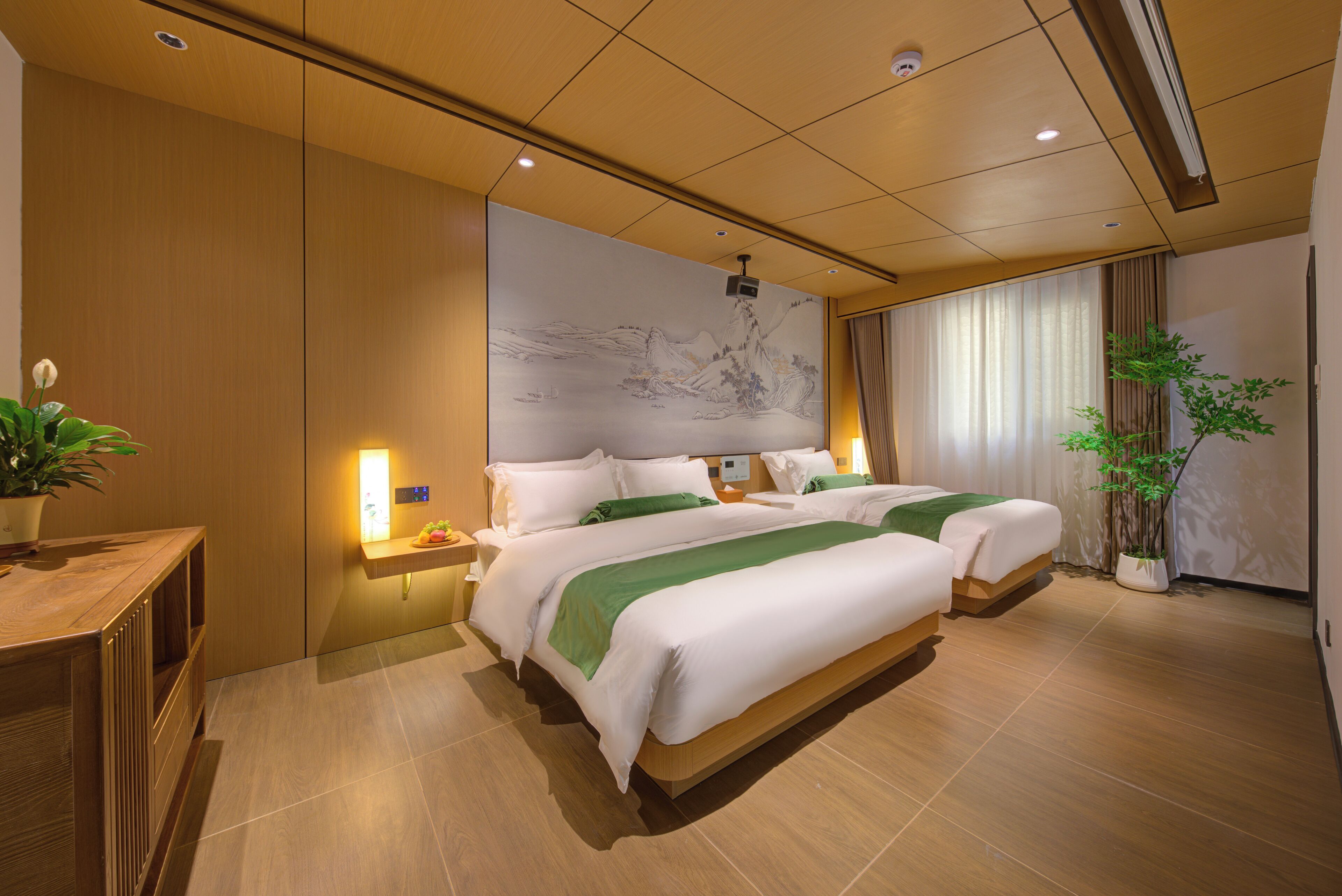 Hotelkamer met twee bedden, een groot muurdecor, een potplant en een houten bureau.