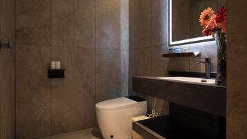 Ein modernes Badezimmer mit einer weißen Toilette, einem dunklen Waschbecken und einem Spiegel darüber.