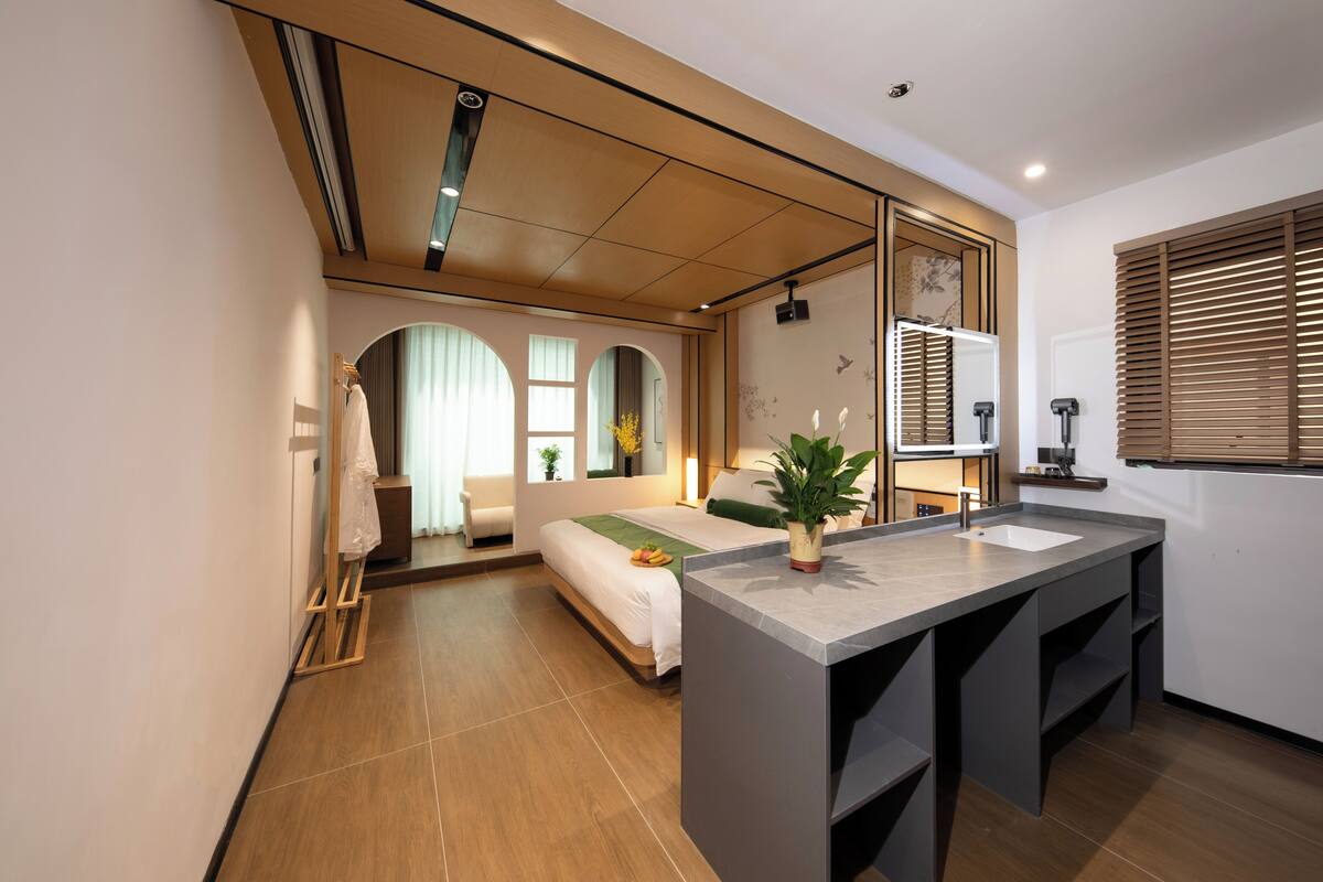 Habitación de hotel moderna con una cama grande, un escritorio pequeño, un baño y vistas a la ciudad.