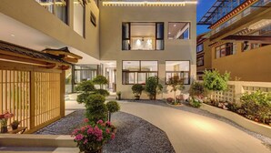 Un edificio moderno de varios pisos con un patio que incluye plantas en macetas y una terraza de madera.