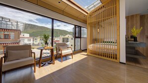 Una habitación amplia con ventanas grandes, suelo de madera, un sofá, una mesita y una partición de madera.