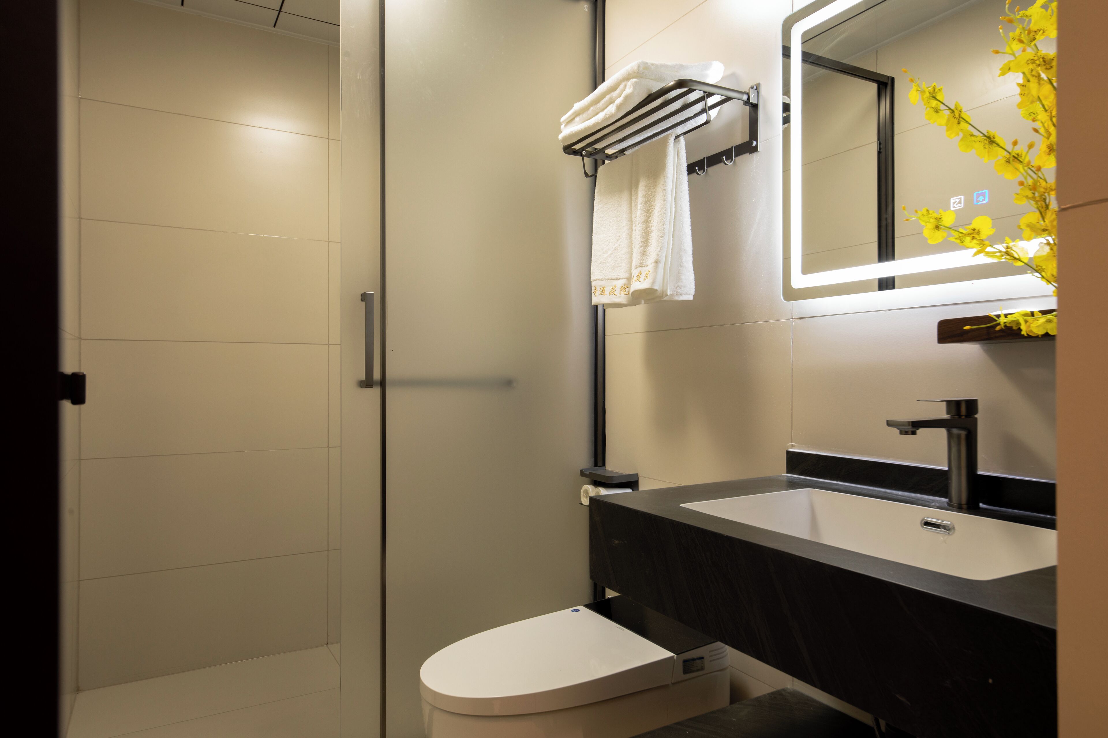 A modern bathroom with a white toilet, a black sink, and a mirror above the sink.