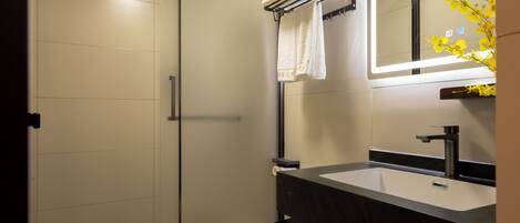 A modern bathroom with a white toilet, a black sink, and a mirror above the sink.