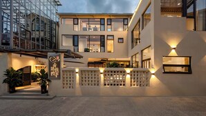 Un hotel moderno con fachada de vidrio, una entrada bien iluminada y un patio con plantas.