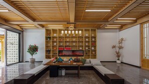 Un interior moderno con techo de madera, un reloj grande en la pared y un área de descanso con mesa y sillas.