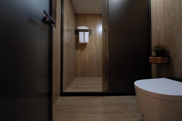A modern bathroom with a wooden floor, a white bathtub, and a towel rack with towels. - The wonderland homestay (Deqin)