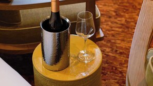 A room with a wooden chair, a small round table, a bottle of wine, and a wine glass. - Confidential Room 1, a Stone's Throw From the Louvre (Paris)