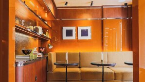 A compact kitchen with wooden cabinets, a built-in stove, and a tiled backsplash. There is a seating area with a sofa and two small tables. - Confidential Room 1, a Stone's Throw From the Louvre (Paris)