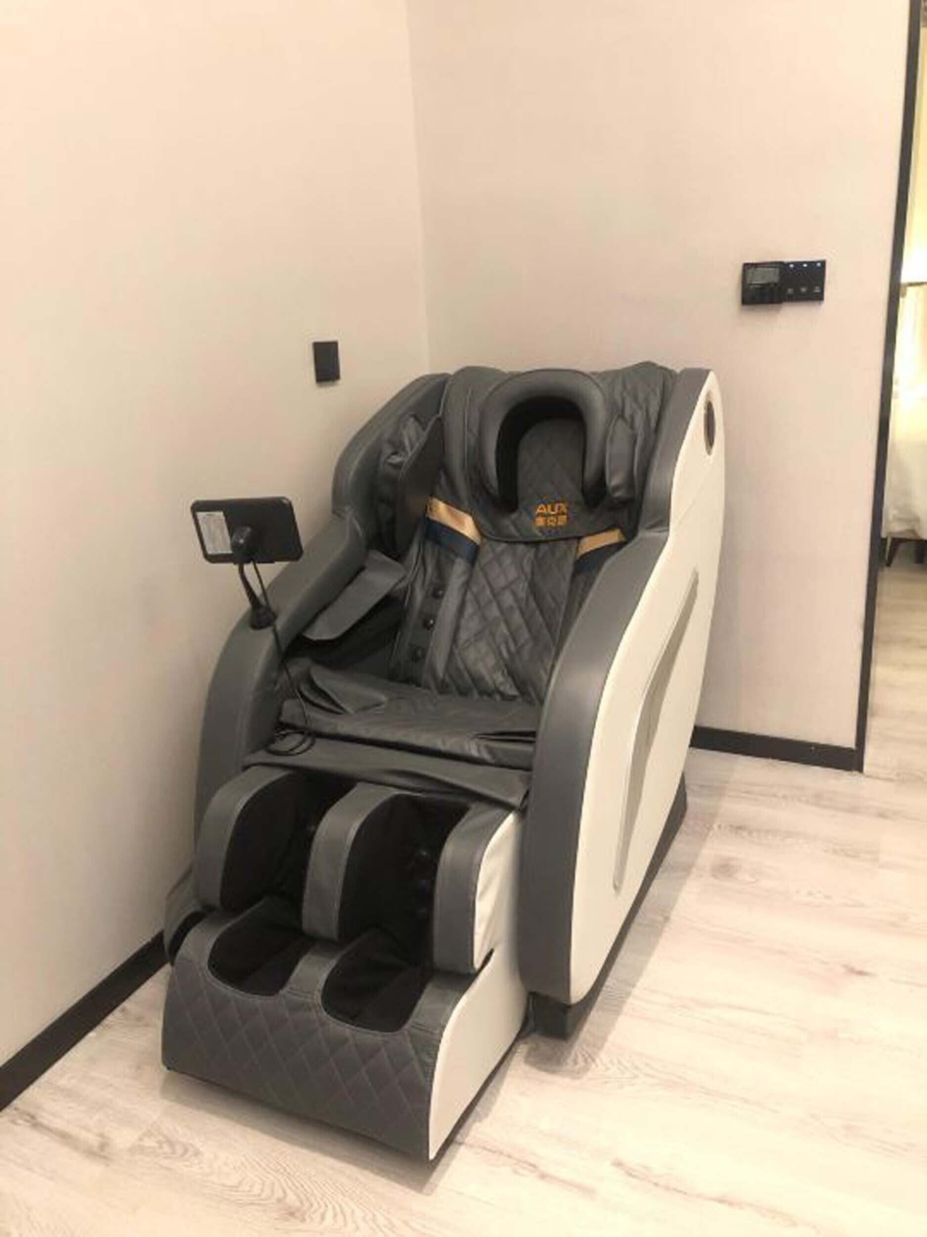 Un fauteuil de massage doté d’un panneau de commande, d’un repose-pieds et d’un siège rembourré.