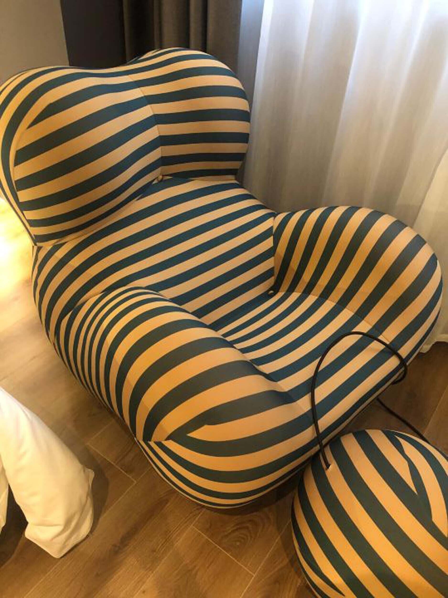 A striped armchair with a matching ottoman, positioned on a wooden floor.