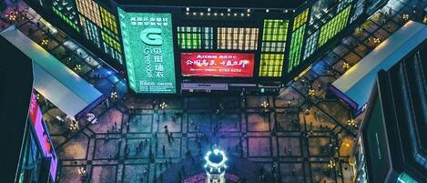 A modern building with multiple illuminated signs and a central circular plaza with a fountain.