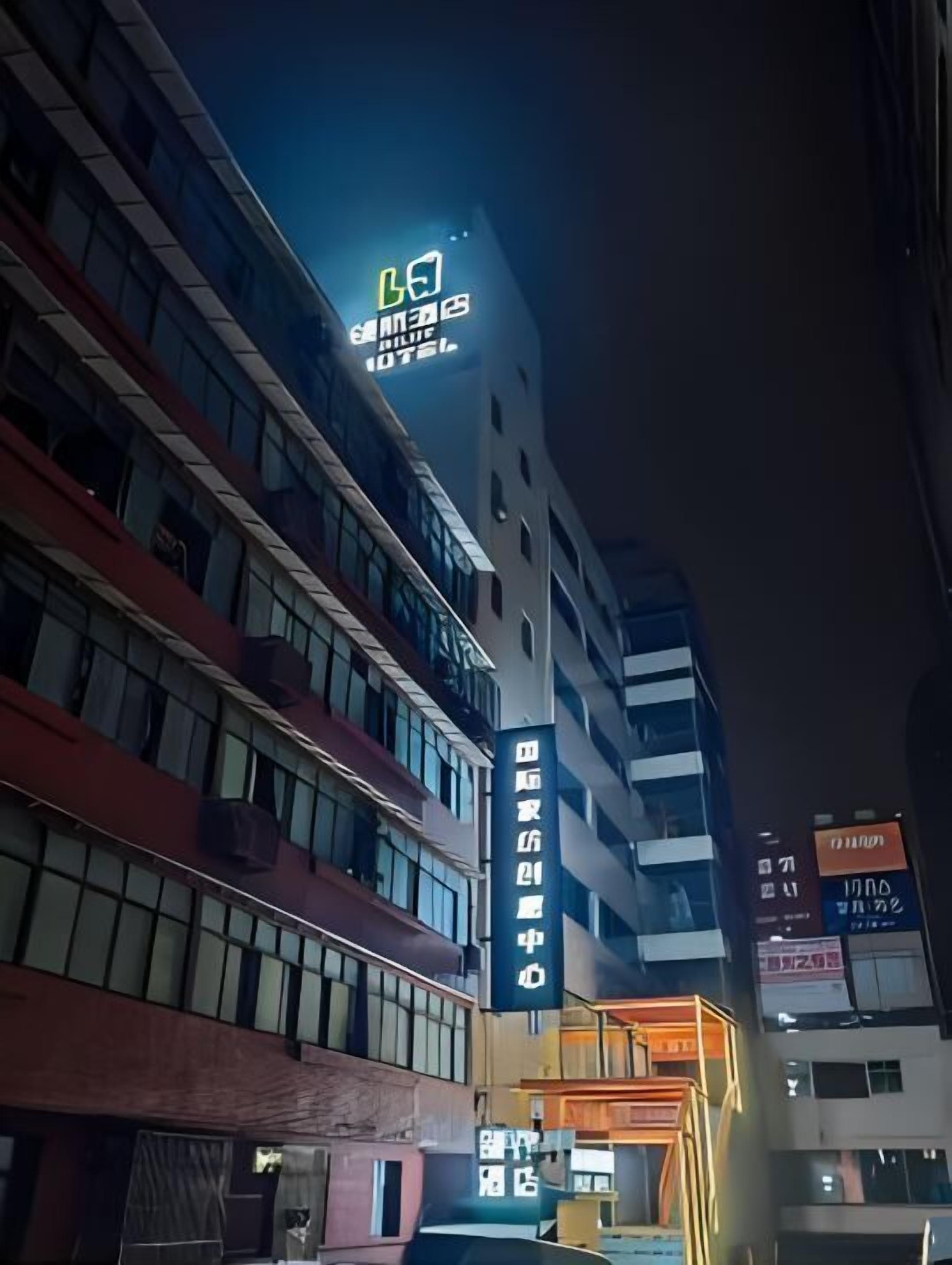 Un immeuble à plusieurs étages doté d’une enseigne lumineuse, comprenant une grande enseigne d’hôtel et une enseigne indiquant un centre d’affaires.