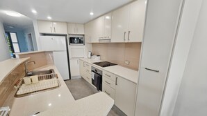 Una cocina moderna con armarios blancos, un lavamanos de acero inoxidable, un microondas y un lavavajillas.