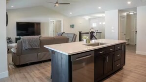 A modern kitchen with a central island, dark cabinetry, and a ceiling fan.