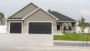 A modern two-story house with a garage, a front porch, and a well-maintained lawn.