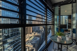 A modern interior with large windows, a round glass table, and a view of the cityscape. - Sydney Luxe Observatory Home | City, Pool & Gym (Sydney)