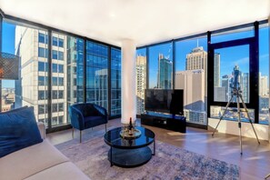 A modern living room with a large TV, a glass coffee table, and a sofa.