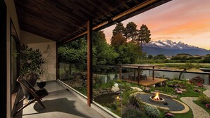 En modern uteplats med en eldstad, en frodig trädgård och utsikt över bergen.