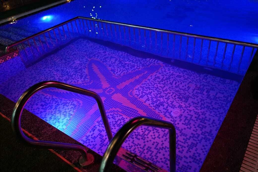 A pool with a geometric pattern on the floor, surrounded by a metal railing.