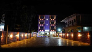 A multi-story building with illuminated windows and a sign for Soham Resort. - Soham Resort Diveagar (Shrivardhan)