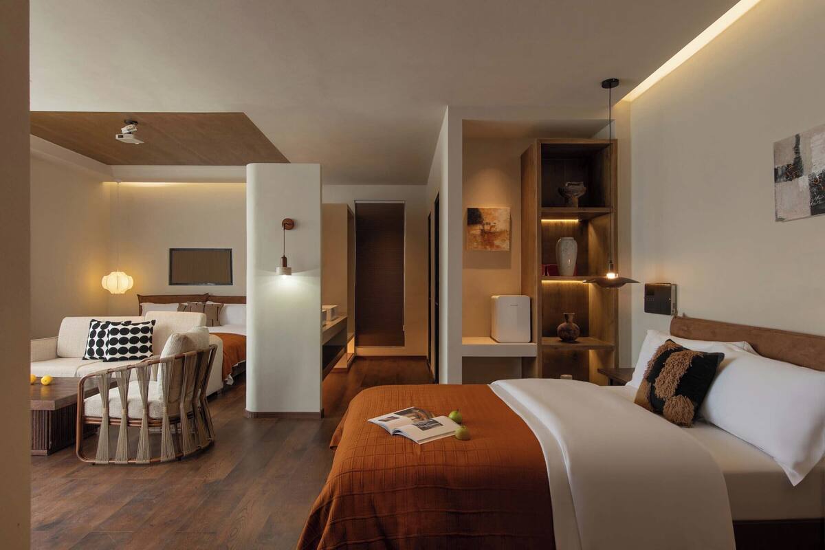Une chambre d’hôtel moderne équipée d’un lit, d’un canapé, d’une chaise, d’un bureau et d’une bibliothèque.