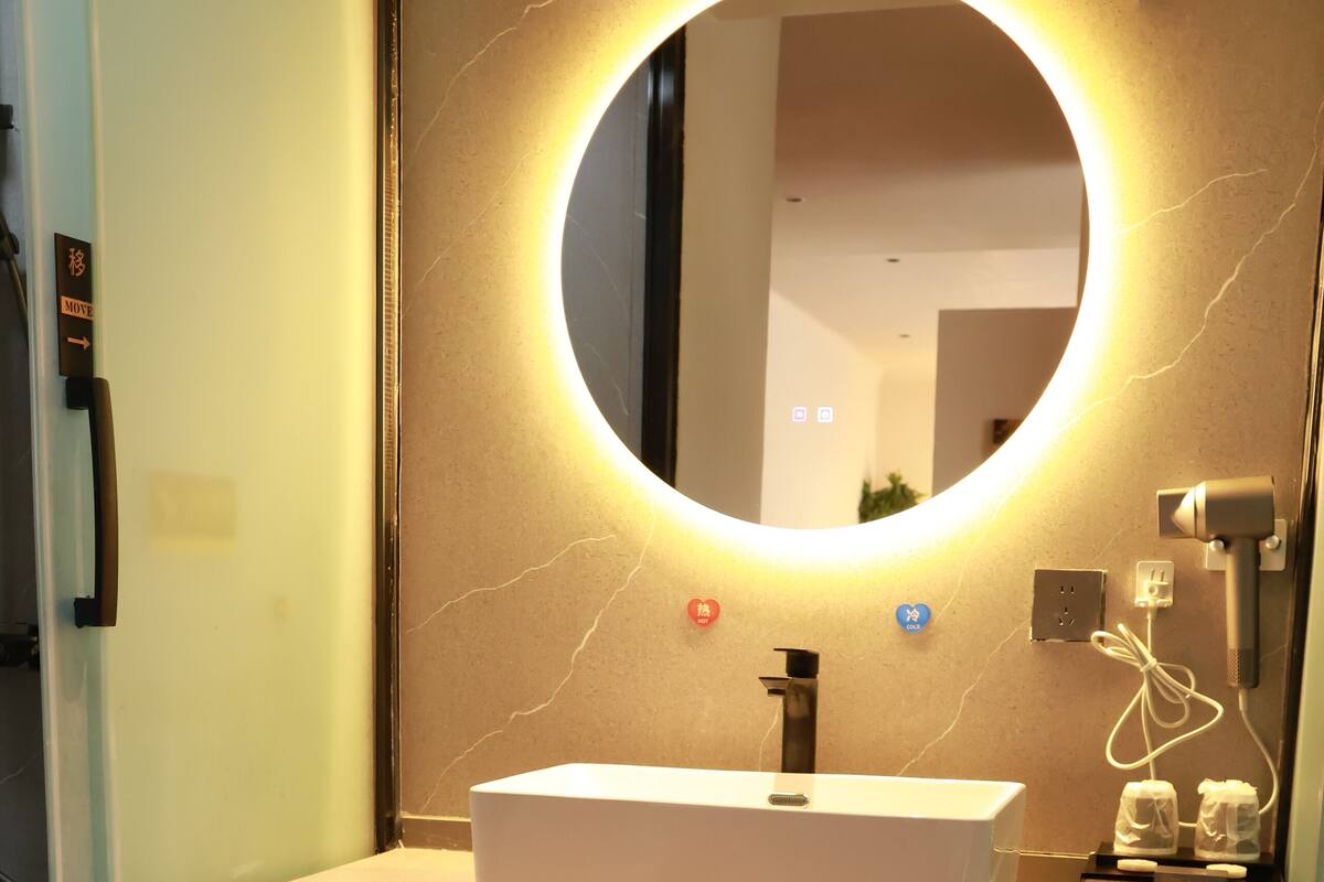 Une salle de bain moderne avec un miroir rond, un lavabo blanc et un espace de rangement intégré pour les chaussures.