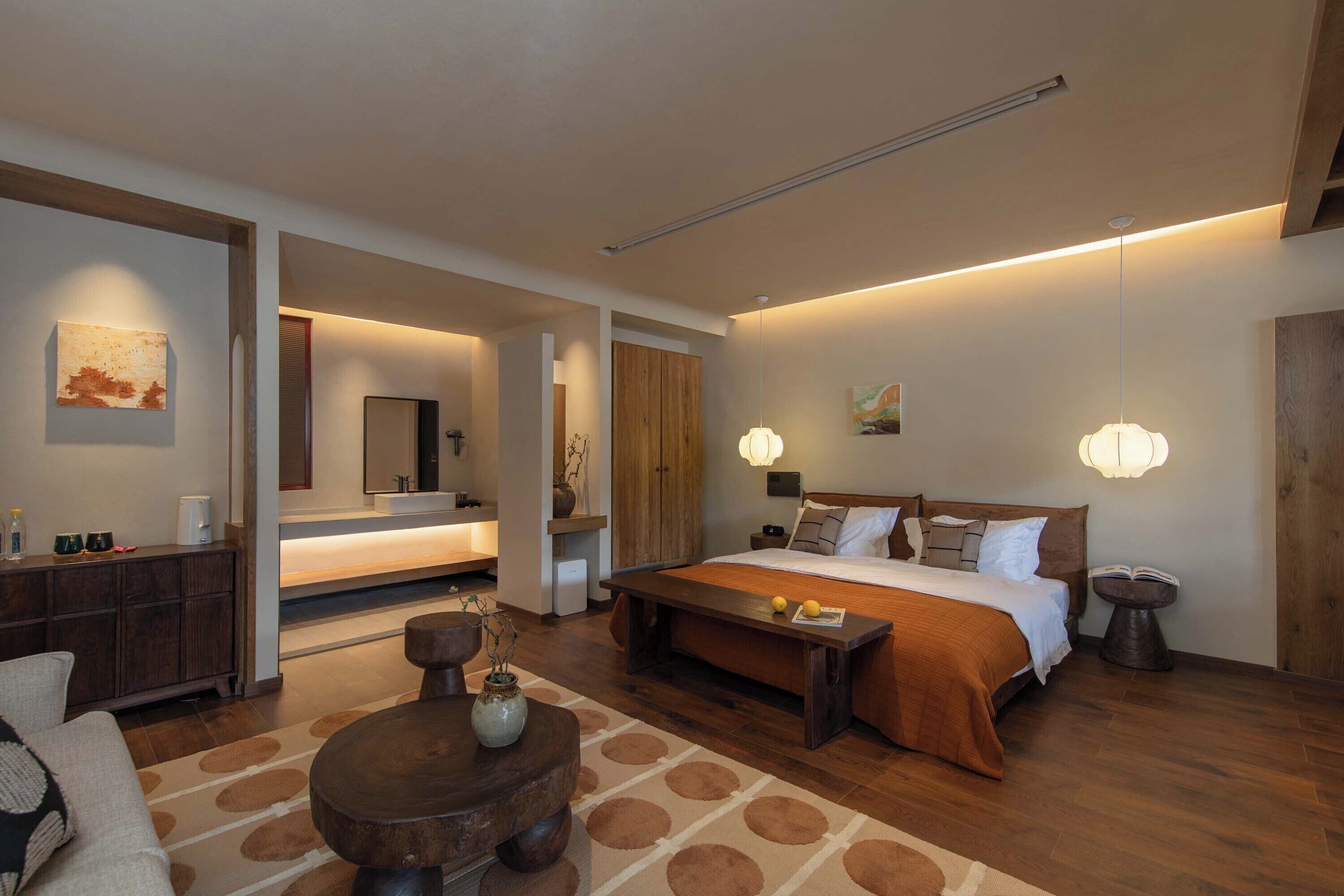 Un dormitorio moderno con una cama grande, mesitas de noche, un banco de madera y una mesita auxiliar.
