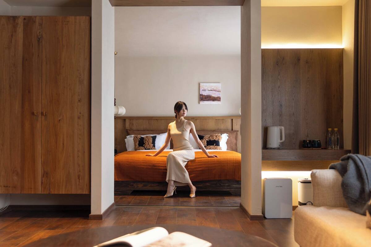 Une chambre moderne avec une armoire en bois, un lit doté d’une tête de lit orange, une table de chevet et une petite lampe de chevet.