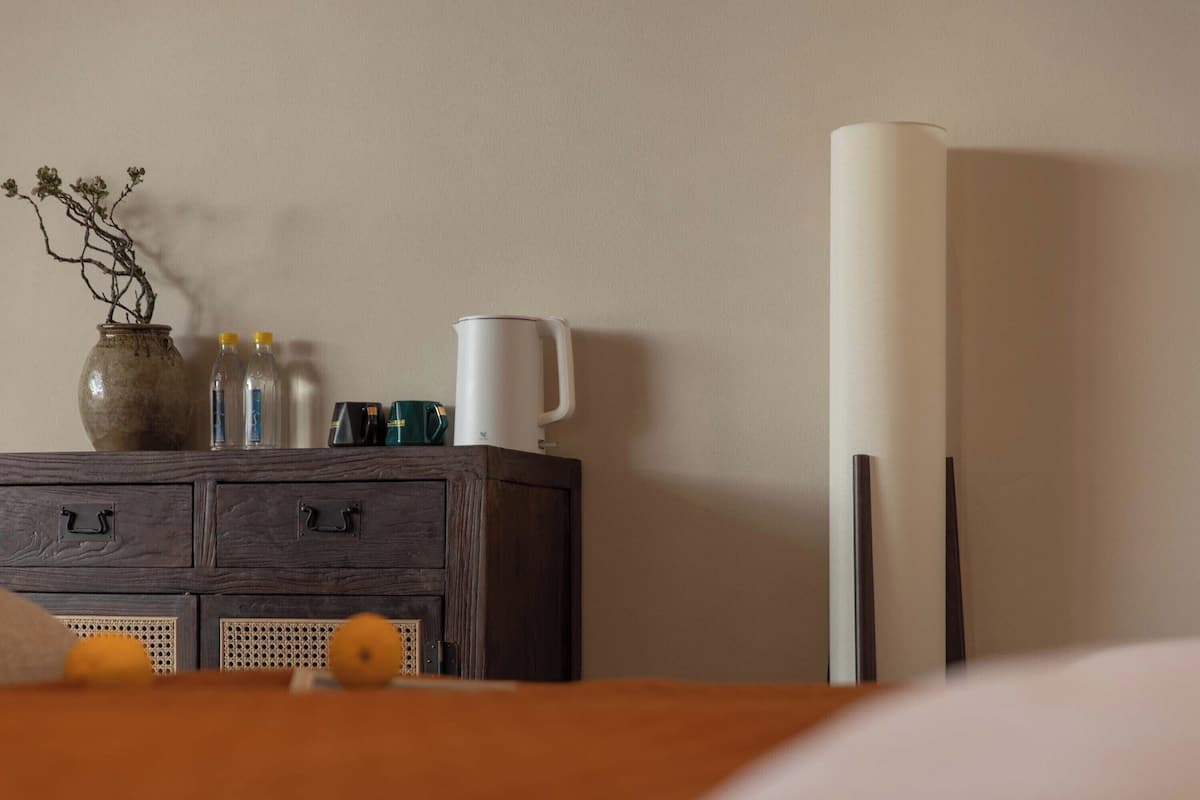 Une commode en bois sur laquelle sont posés un vase, des bouteilles et une tasse blanche.
