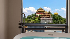 Un baño con un ventanal grande, una bañera y vistas a un edificio tradicional.