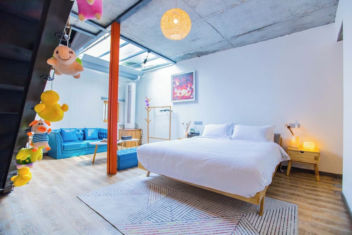 A modern bedroom with a large bed, a blue sofa, and a wooden floor.