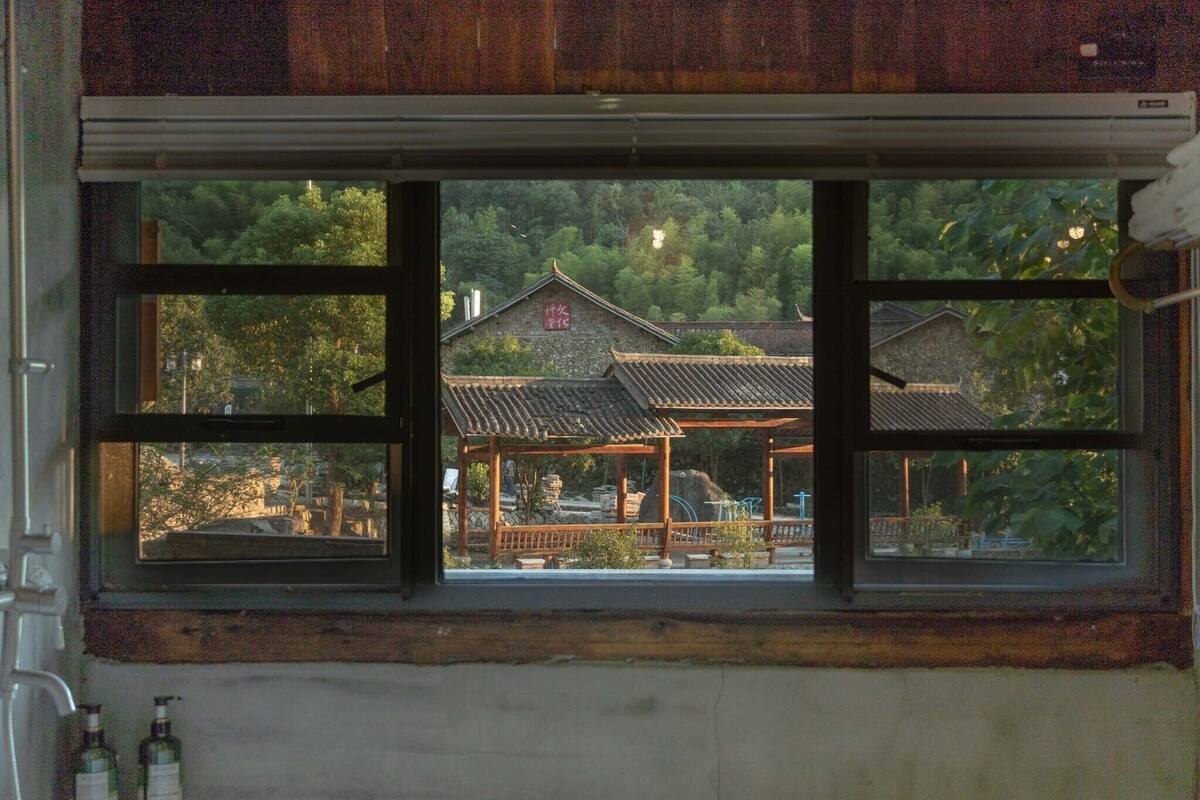 A traditional Japanese building with a wooden structure and tiled roof, viewed through a window with a wooden frame.