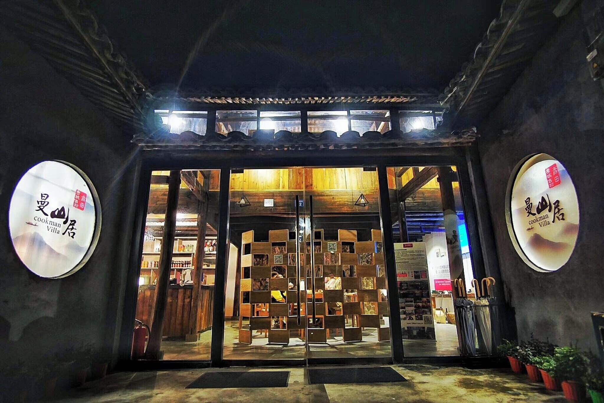 La entrada de Cookman Villa, con fachada de madera tradicional, techo de tejas y puerta de cristal que da al interior.