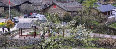 A traditional village with stone buildings, a central pavilion, and a stone wall.
