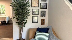 Ein gemütliches Wohnzimmer mit einer Couch, einem Blumentopf und einer Treppe.