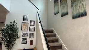 Eine Treppe mit Handlauf, einem Deckenventilator und mehreren gerahmten Bildern an den Wänden.